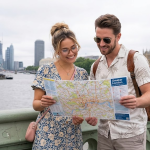 Couple exploring London with a map on Westminster Bridge, Big Ben and Thames River in the background